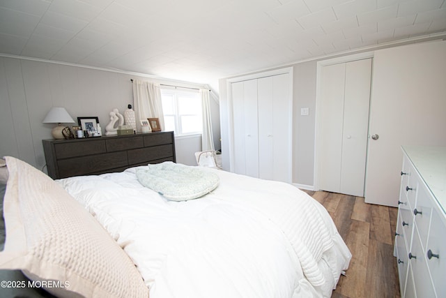 bedroom featuring light wood finished floors and two closets