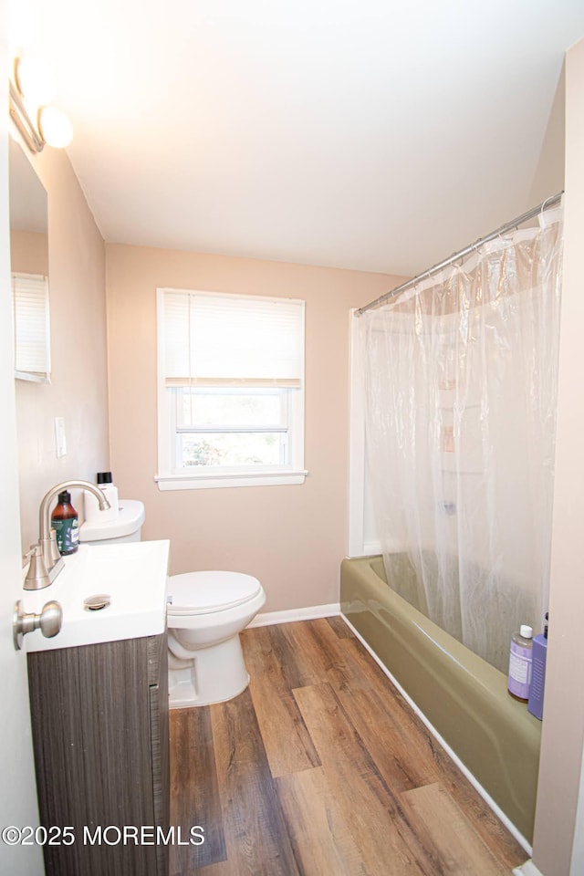 full bath with shower / bath combo, baseboards, toilet, wood finished floors, and vanity