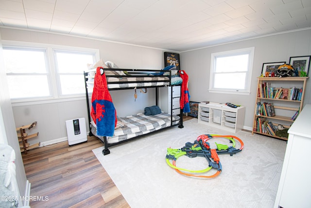 bedroom featuring ornamental molding, baseboards, and wood finished floors