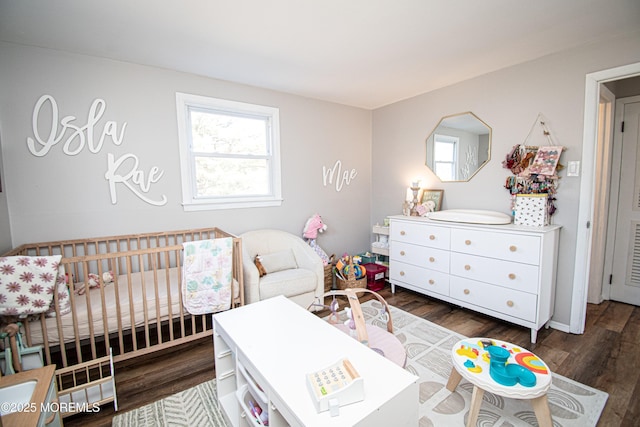 bedroom featuring dark wood finished floors and a crib