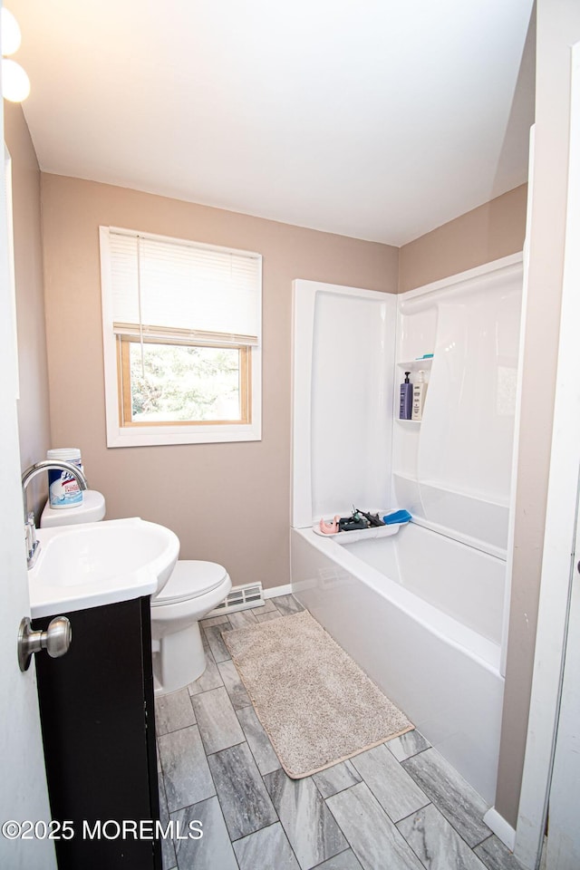 bathroom with toilet, shower / bathing tub combination, vanity, and baseboards