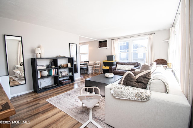 living room with dark wood-type flooring, an AC wall unit, and baseboards