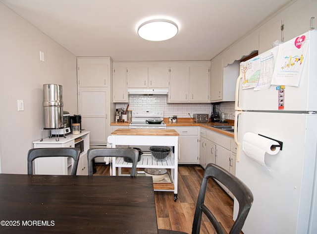 kitchen featuring white appliances, white cabinets, dark wood-style flooring, under cabinet range hood, and backsplash