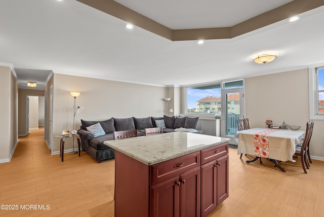 kitchen featuring reddish brown cabinets, crown molding, light wood-style flooring, open floor plan, and light stone countertops