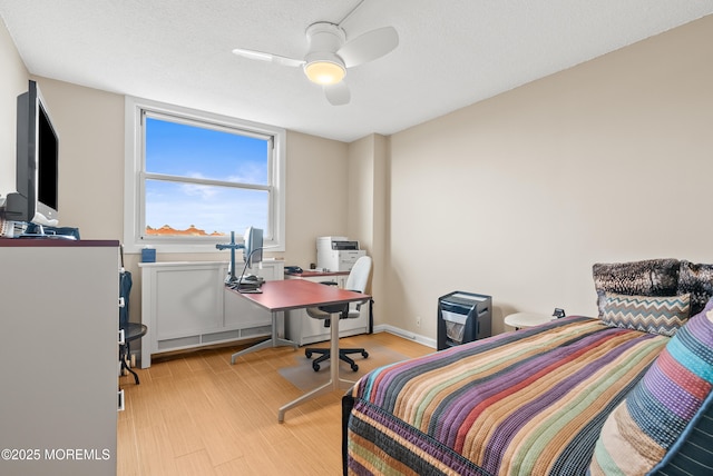 bedroom with light wood-type flooring, ceiling fan, a textured ceiling, and baseboards