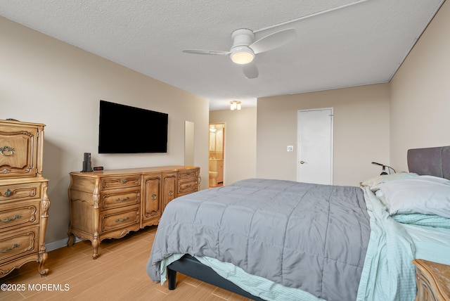 bedroom with a ceiling fan, connected bathroom, light wood-style flooring, and a textured ceiling