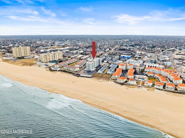 drone / aerial view featuring a view of city, a water view, and a beach view