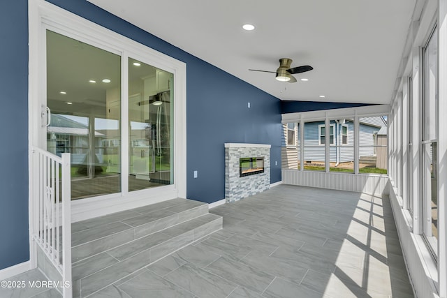 sunroom / solarium featuring lofted ceiling, a fireplace, and a ceiling fan