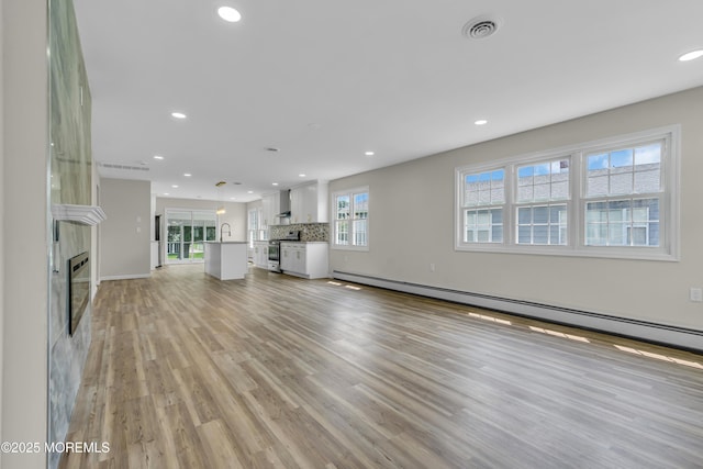 unfurnished living room with light wood-style floors, recessed lighting, and a tile fireplace