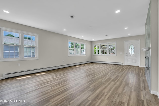 unfurnished living room with light wood-style floors, baseboard heating, and recessed lighting