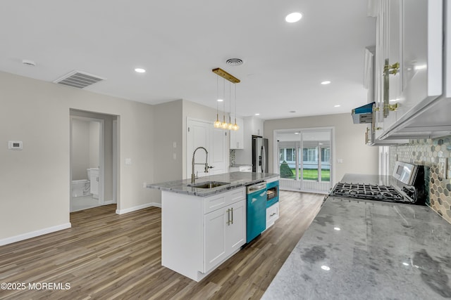 kitchen with pendant lighting, stainless steel appliances, white cabinetry, a sink, and an island with sink