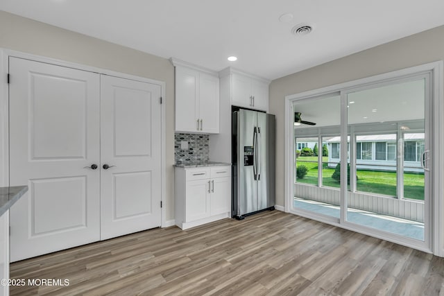 kitchen featuring light stone counters, white cabinets, and stainless steel refrigerator with ice dispenser