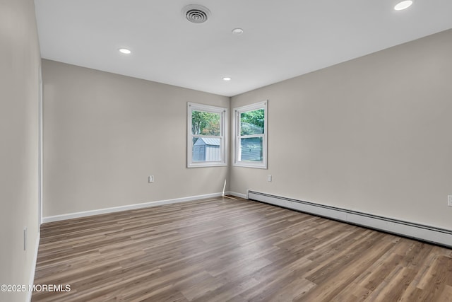 unfurnished room with visible vents, baseboards, light wood-style flooring, a baseboard heating unit, and recessed lighting