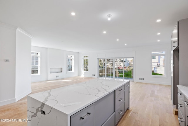 kitchen featuring open floor plan, light stone countertops, and gray cabinetry