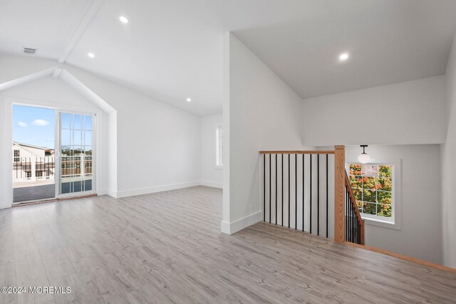 additional living space with lofted ceiling, light wood-type flooring, visible vents, and a healthy amount of sunlight