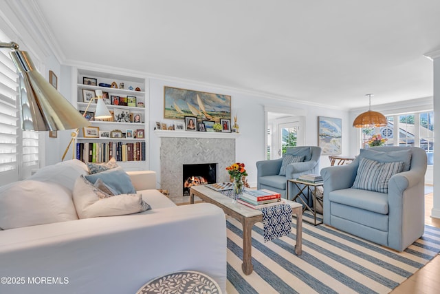 living area featuring crown molding, a fireplace, plenty of natural light, and built in shelves