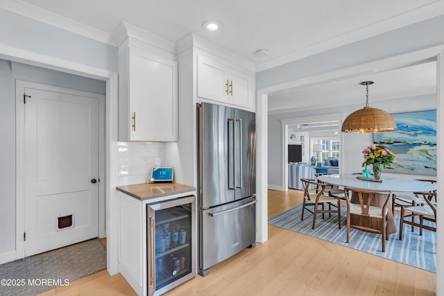 kitchen with wine cooler, high end refrigerator, light wood-style flooring, and crown molding