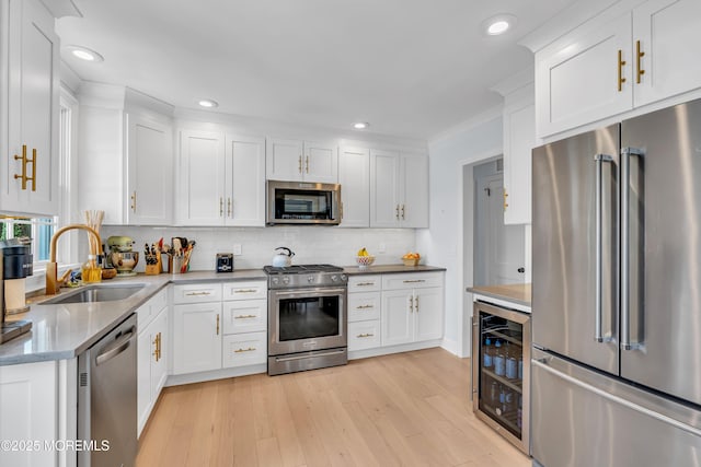 kitchen with appliances with stainless steel finishes, wine cooler, white cabinetry, and a sink