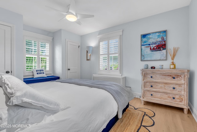 bedroom featuring baseboards, wood finished floors, a ceiling fan, and radiator