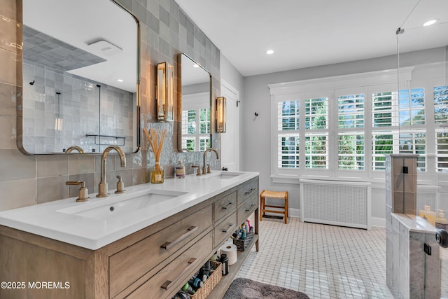 bathroom with tasteful backsplash, a sink, radiator heating unit, and double vanity