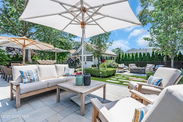 view of patio featuring outdoor dining space, fence, an outbuilding, and an outdoor living space with a fire pit