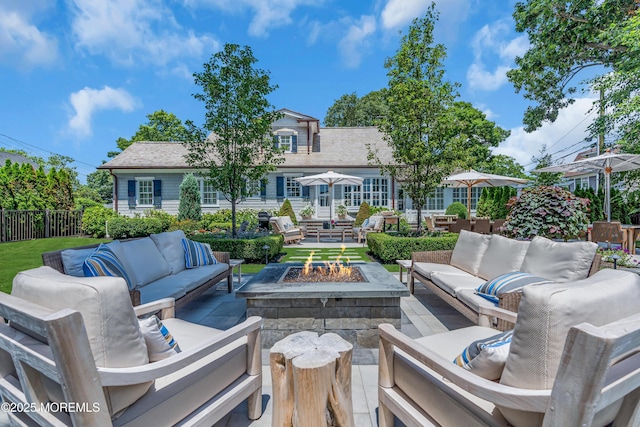 rear view of property featuring a patio area, an outdoor living space with a fire pit, and fence