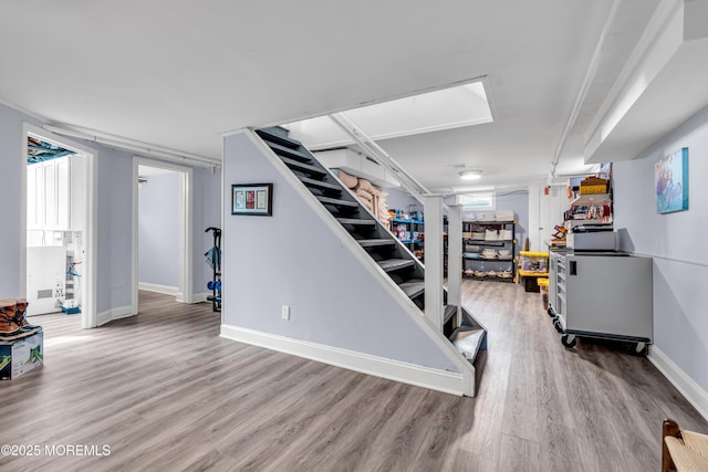 finished basement with baseboards, stairway, and wood finished floors