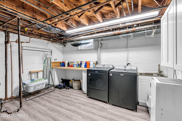 laundry room with light wood-style floors, cabinet space, a sink, and washing machine and clothes dryer