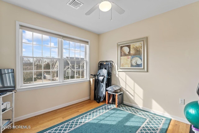 workout room featuring a ceiling fan, baseboards, visible vents, and wood finished floors