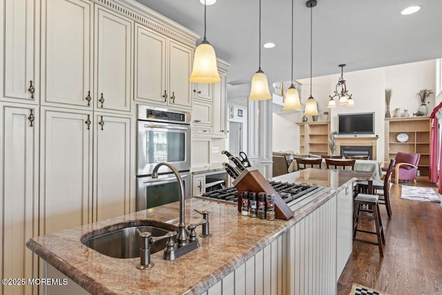 kitchen with a breakfast bar, decorative light fixtures, cream cabinets, double oven, and light stone countertops