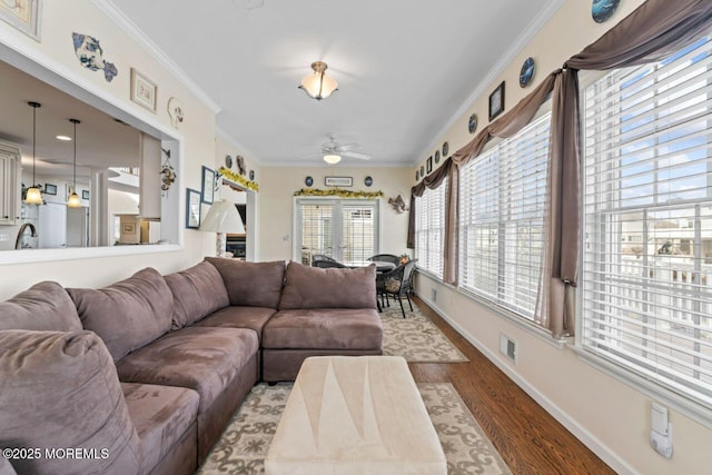 living room featuring visible vents, ornamental molding, ceiling fan, wood finished floors, and baseboards