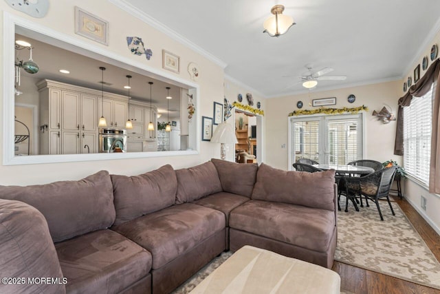 living area featuring crown molding, baseboards, ceiling fan, and wood finished floors