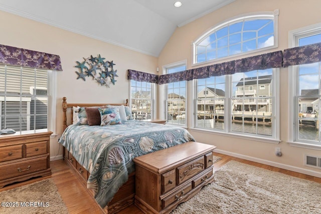 bedroom with vaulted ceiling, light wood finished floors, visible vents, and baseboards