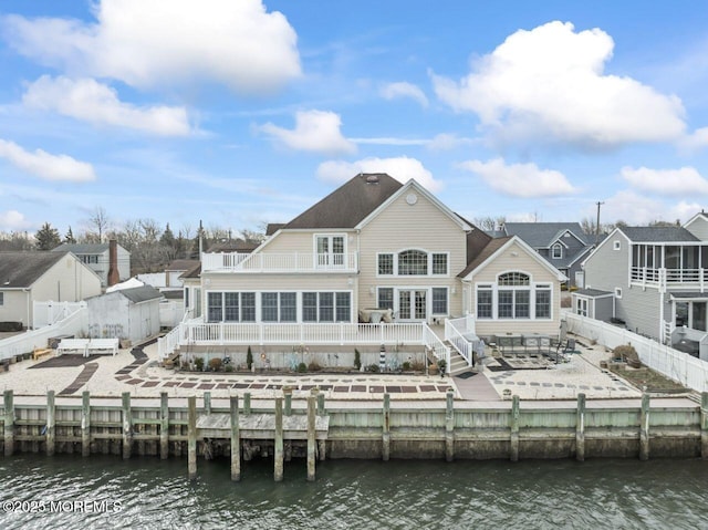 rear view of house with a sunroom, a fenced backyard, a residential view, a deck with water view, and a patio area