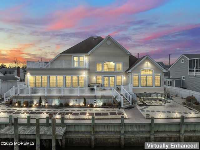 back of property at dusk with a deck, a patio, fence private yard, and a balcony