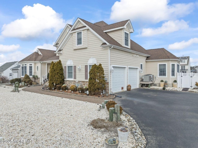 view of front facade with a garage, driveway, a shingled roof, and stone siding