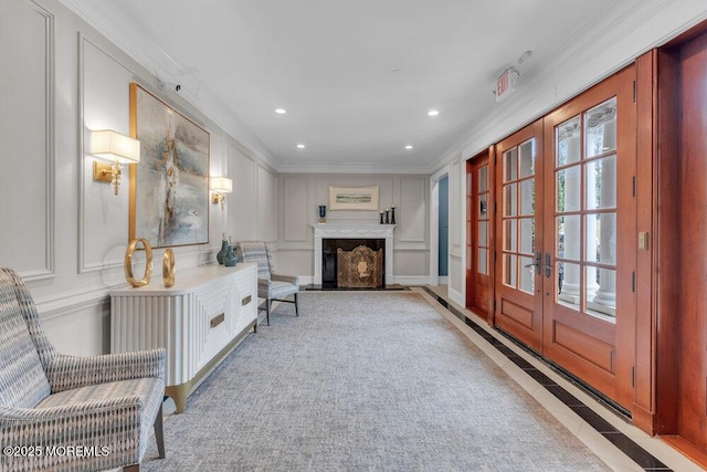 sitting room featuring a fireplace with flush hearth, ornamental molding, french doors, a decorative wall, and recessed lighting