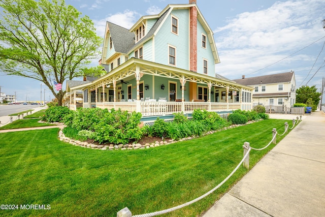 view of front of property with a front lawn, a chimney, fence, and a gambrel roof