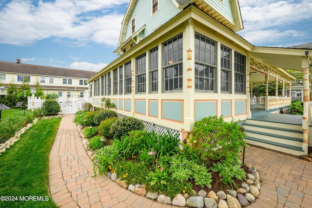 view of side of property with fence and a sunroom