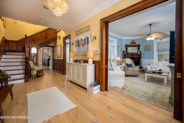 interior space with a wainscoted wall, stairs, crown molding, light wood-style floors, and a fireplace