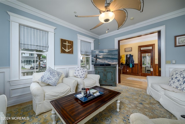 living area with ornamental molding, light wood-type flooring, and wainscoting