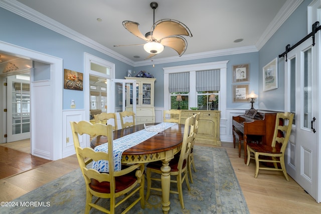 dining room with a barn door, light wood-style flooring, and a healthy amount of sunlight