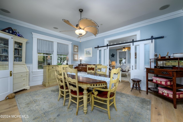 dining room featuring a barn door, a ceiling fan, and crown molding