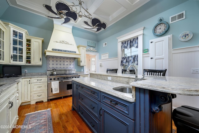 kitchen with range with two ovens, a breakfast bar, coffered ceiling, a sink, and glass insert cabinets