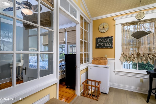 interior space with a wainscoted wall, wood finished floors, and crown molding