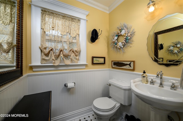 half bathroom featuring toilet, a wainscoted wall, ornamental molding, and a sink