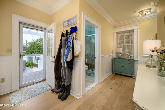 doorway to outside featuring a wainscoted wall, ornamental molding, and light wood-style floors