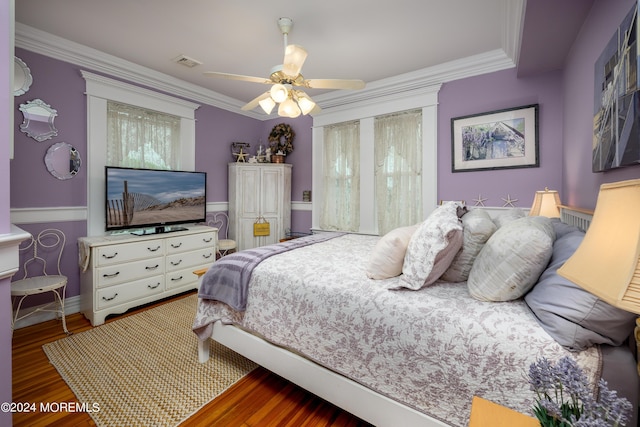 bedroom featuring ceiling fan, a wainscoted wall, dark wood-style flooring, visible vents, and crown molding