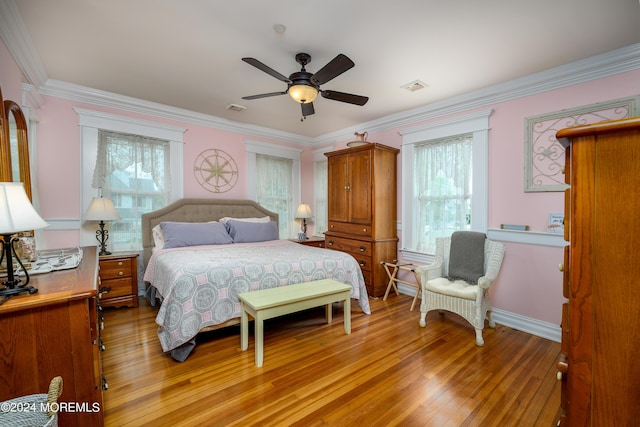 bedroom with ornamental molding, light wood finished floors, visible vents, and baseboards