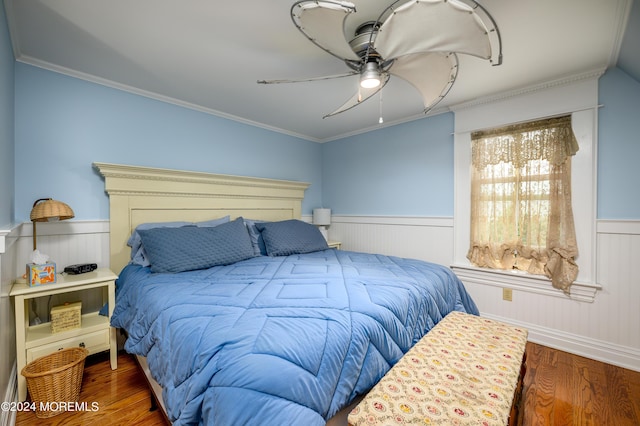 bedroom with dark wood-style floors, wainscoting, ornamental molding, and ceiling fan